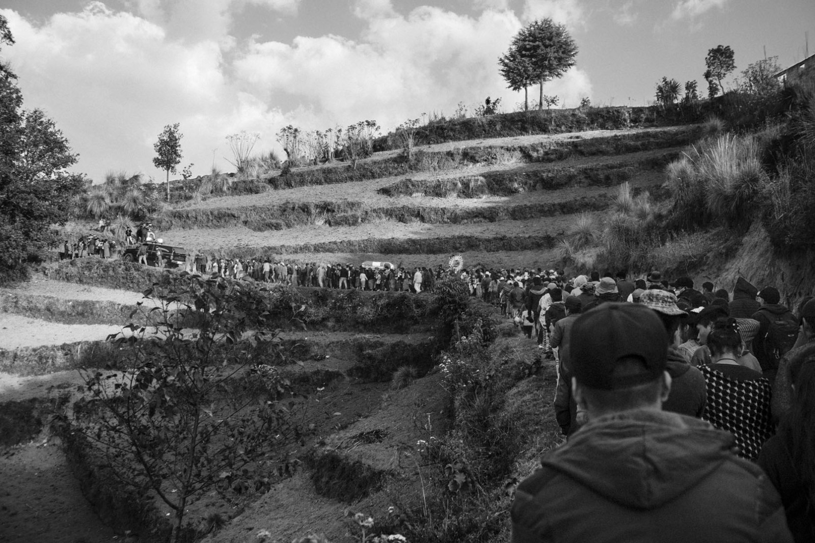 People move towards the Tuilelen's cemetery during the funeral of Rivaldo Jimenez Ramirez, Santa Cristina Garcia, and Ivan Gudiel Pablo in Comitancillo, Guatemala, on March 14, 2021.
On January 22, 2021, nineteen charred bodies were found on a country road in Tamaulipas, Mexico's northeastern state bordering the United States. Sixteen of the victims were Guatemalan, thirteen from the same village, Comitancillo, and the others were of Mexican descent. The bodies were inside a pickup truck, hit by 113 bullets, and burned.  
The massacre, according to investigators, would be linked to a dispute between criminal groups for the control of migrant routes. Twelve police officers are under trial for allegedly having committed the crime.
Each migrant had sold properties and incurred debts to pay up to 11 thousand dollars to a trafficker who had ensured they would have entered the United States. Their goal was to find a job to pay the debt back and send money to their families. The entire community welcomed journalists and photographers in their homes and during the three-day funeral processions hoping that, by the world knowing their suffering, such an event would not occur again.