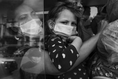 A child watches out from a bus window in Honduras, close to the border with Guatemala, on January 15, 2021.
Despite COVID-19-related border closures, refugees and migrants from Central America continued to flee their countries and head north throughout 2020 and 2021.
In November, 2020 after hurricanes Eta and Iota hit Central America, flooding and mudslides left 9,3 million victims, of which 3,5 million are children (UNICEF), fueling a significant migration to the United States.
As a ten thousand people caravan gathered in San Pedro Sula in the night between January 14 and 15, the photographer has documented their northward journey, following several families through Guatemala, Mexico, and the United States for seven months in 2021.
The scene depicted in the photograph happened in a gas station parking lot, where the cars and buses were stopping to pick people up. The people on the bus welcomed photographers and journalists to work. A child watches out from a bus window in Honduras, close to the border with Guatemala, on January 15, 2021.
Despite COVID-19-related border closures, refugees and migrants from Central America continued to flee their countries and head north throughout 2020 and 2021.
In November, 2020 after hurricanes Eta and Iota hit Central America, flooding and mudslides left 9,3 million victims, of which 3,5 million are children (UNICEF), fueling a significant migration to the United States.
As a ten thousand people caravan gathered in San Pedro Sula in the night between January 14 and 15, the photographer has documented their northward journey, following several families through Guatemala, Mexico, and the United States for seven months in 2021.
The scene depicted in the photograph happened in a gas station parking lot, where the cars and buses were stopping to pick people up. The people on the bus welcomed photographers and journalists to work.