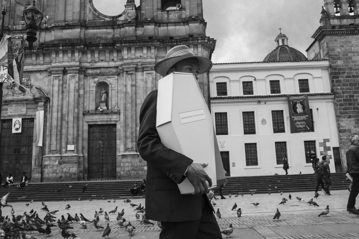 A protestor carries a child-size coffin made of paper in Bolivar square; in Bogotá; to protest the death of Wayuu children in La Guajira.