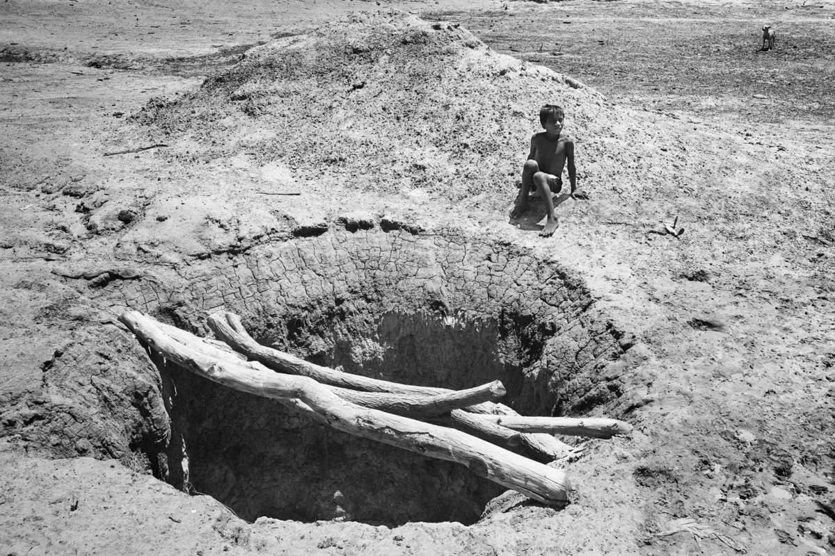 A child sits in front of a well that his community is building to get water.
