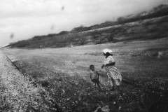 A woman and child wait for a train to pass. The Cerrejon train transports coal 24/7 from the municipality of Albania to Puerto Bolivar, where it takes the route to Europe, United States, South-America, and South-Africa. Coal dust has spoiled the land.