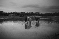 A young girl and a boy fill tanks with rain water in a jagüey - a traditional pool used by the Indigenous Wayuu as a reservoir of water.