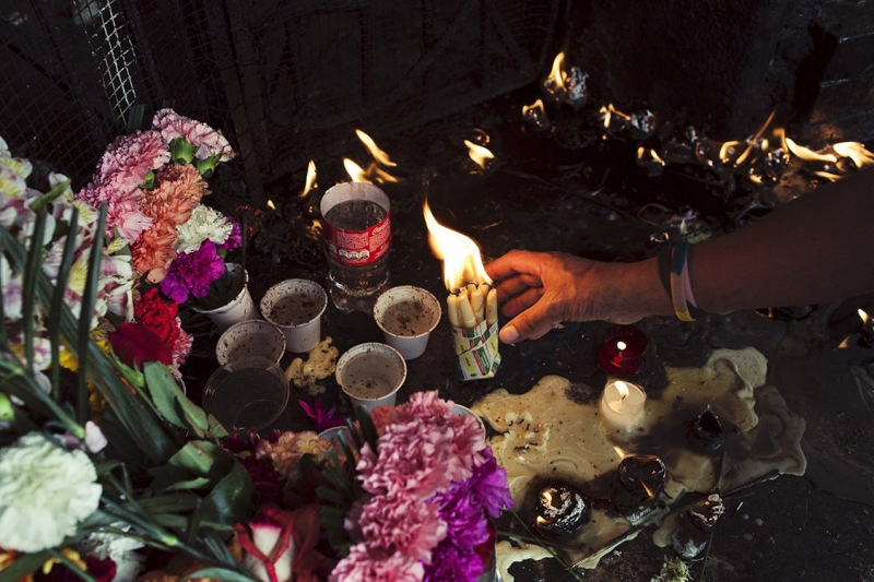 A girl is offering lit candles to the Garabito’s grave in the Central Cementery of Bogota’. Every Monday mornig transgender sex workers and prostitutes give theiroffers of flowers and candles to this grave, asking for protection and fortune for the incoming week of work.
